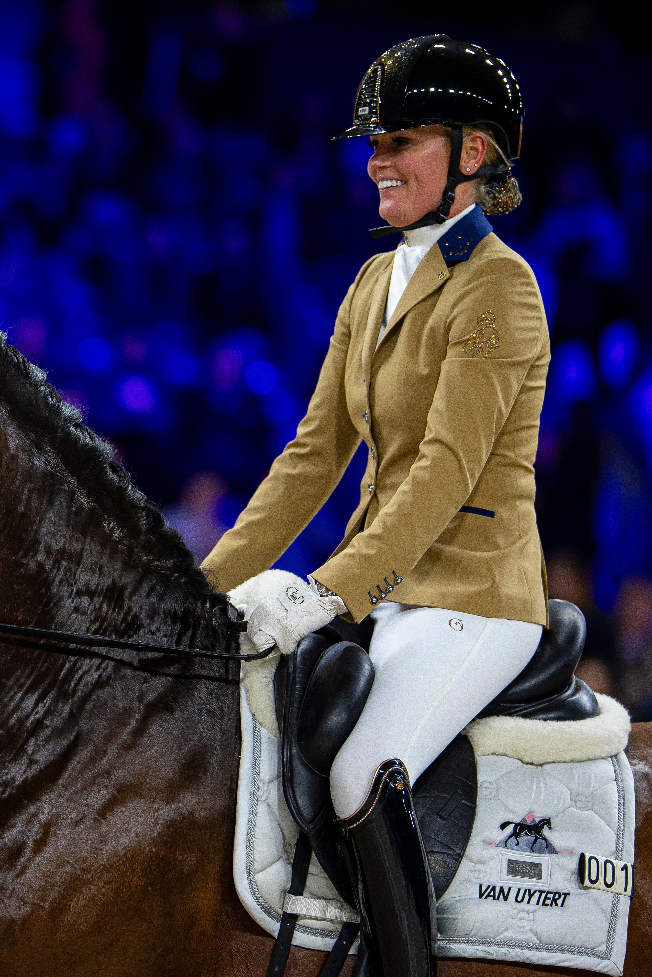 Rider with horse wearing the JuulC x Jumping Amsterdam coat 2024 version, in beige with dark blue accents and Swarovski crystal design and logo